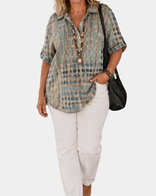 Aurore relaxed printed blouse in sage, worn with white trousers, on a light grey studio background